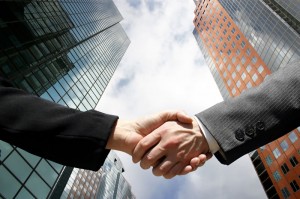 Handshake with buildings and clear sky in the background